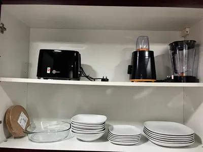 a shelf with a bunch of plates and a blender at Diamond Marina inn, Offers Spacious Apartment 5 min Walk To JBR Beach And METRO in Dubai