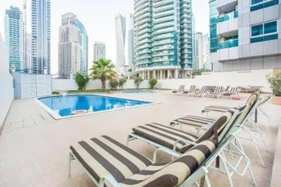 a group of lounge chairs next to a swimming pool at Diamond Marina inn, Offers Spacious Apartment 5 min Walk To JBR Beach And METRO in Dubai