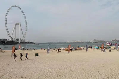 people on a beach with a ferris wheel in the background at Diamond Marina inn, Offers Spacious Apartment 5 min Walk To JBR Beach And METRO in Dubai