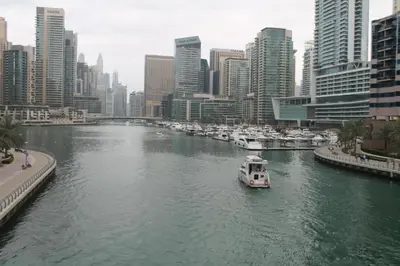 a boat in a river in a city with buildings at Diamond Marina inn, Offers Spacious Apartment 5 min Walk To JBR Beach And METRO in Dubai