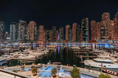 a city at night with boats in a marina at Vida Dubai Marina & Yacht Club, Hotel and Residences, Luxurious 2BR in Dubai