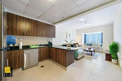 a kitchen with wooden cabinets and a living room at Lux Sea view 1BR in Dubai Marina in Dubai