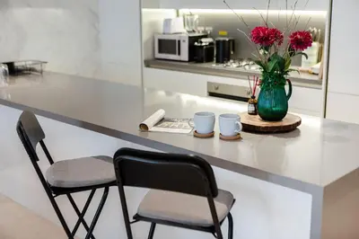 a kitchen with a counter with two chairs and a vase with flowers at Luxury 1BR Apartment with Burj Khalifa View at Sterling in Dubai