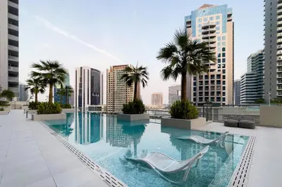 a pool on the roof of a building with palm trees at Luxury 1BR Apartment with Burj Khalifa View at Sterling in Dubai