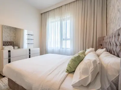 a bedroom with a large white bed and a window at Modern 1BR in Park Heights 2, Dubai Hills in Dubai