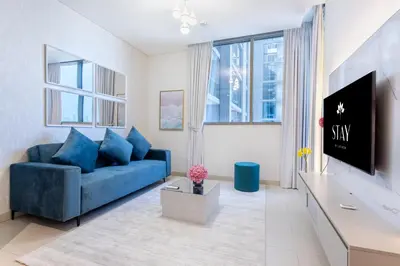 a living room with a blue couch and a tv at STAY BY LATINEM Luxury 1BR Holiday Home CVR B1701 near Burj Khalifa in Dubai