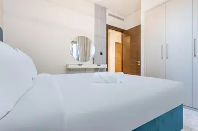 a white bedroom with a large bed and a mirror at STAY BY LATINEM Luxury 1BR Holiday Home CVR B1701 near Burj Khalifa in Dubai