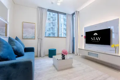 a living room with a blue couch and a tv at STAY BY LATINEM Luxury 1BR Holiday Home CVR B1701 near Burj Khalifa in Dubai