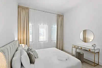 a white bedroom with a bed and a mirror at Luxury 4BR Townhouse Palm Jumeirah in Dubai