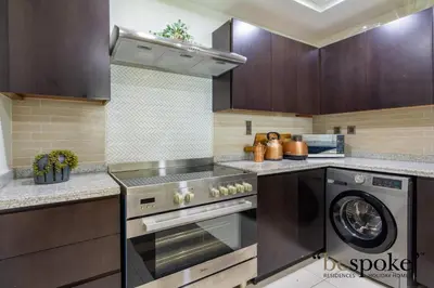 a kitchen with a stove and a washing machine at Bespoke Holiday Homes - Palm Jumeirah -2 Bedroom Sea View with Beach Access, Balqis in Dubai