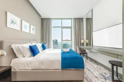 a bedroom with a bed and a desk and a window at Damac Maison Prive DVR Vacation Homes in Dubai