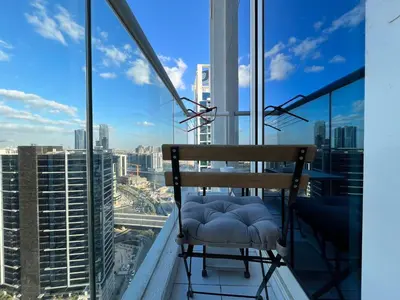 a chair on a balcony with a view of the city at Damac Maison Prive DVR Vacation Homes in Dubai