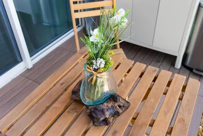 a vase filled with flowers sitting on a wooden bench at Burj View Apartment at Vera, Business Bay in Dubai