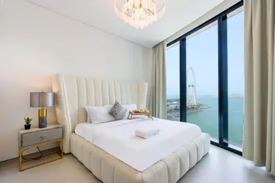 a bedroom with a large white bed and large windows at Livbnb Premium 3BR at Address JBR Posh Interiors with Sea and Ain Views in Dubai