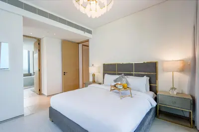 a bedroom with a large white bed and a chandelier at Livbnb Premium 3BR at Address JBR Posh Interiors with Sea and Ain Views in Dubai