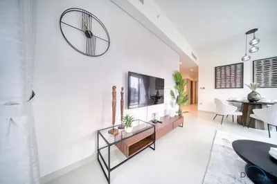 a living room with white walls and a large clock on the wall at Stylish 2BR with Burj Khalifa View at Burj Royale Downtown Dubai by Deluxe Holiday Homes in Dubai