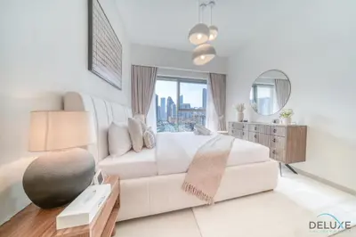 a white bedroom with a white couch and a mirror at Stylish 2BR with Burj Khalifa View at Burj Royale Downtown Dubai by Deluxe Holiday Homes in Dubai