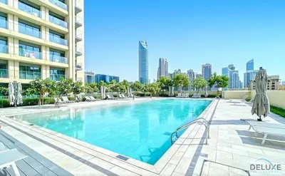 a swimming pool with chairs and a building at Stylish 2BR with Burj Khalifa View at Burj Royale Downtown Dubai by Deluxe Holiday Homes in Dubai