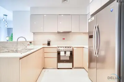 a kitchen with white cabinets and a stainless steel refrigerator at Stylish 2BR with Burj Khalifa View at Burj Royale Downtown Dubai by Deluxe Holiday Homes in Dubai