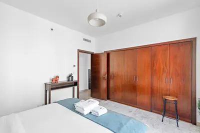 a bedroom with a bed and wooden cabinets at StoneTree - Spacious 1 BR Apartment in Dubai Marina in Dubai