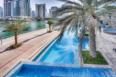 a swimming pool with palm trees next to a river at StoneTree - Spacious 1 BR Apartment in Dubai Marina in Dubai
