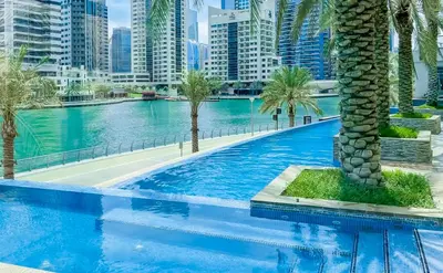 a large swimming pool with palm trees and buildings at StoneTree - Spacious 1 BR Apartment in Dubai Marina in Dubai