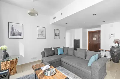 a living room with a gray couch and a table at StoneTree - Spacious 1 BR Apartment in Dubai Marina in Dubai