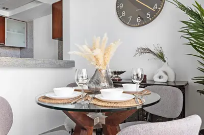 a dining room table with a clock on the wall at StoneTree - Spacious 1 BR Apartment in Dubai Marina in Dubai