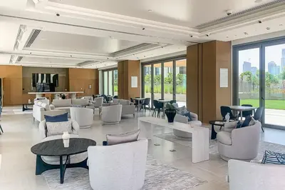 a lobby with white chairs and tables and windows at Frank Porter - Downtown Views II in Dubai