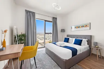 a bedroom with a bed and a desk and a window at StoneTree - Cozy 1 BR Apartment in Al Furjan in Dubai