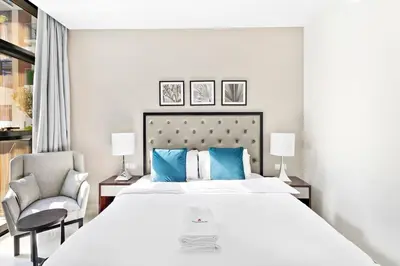 a bedroom with a large white bed and a chair at StoneTree - Furnished 1BR minutes of drive away to Expo 2020 in Dubai