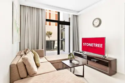 a living room with a couch and a flat screen tv at StoneTree - Furnished 1BR minutes of drive away to Expo 2020 in Dubai