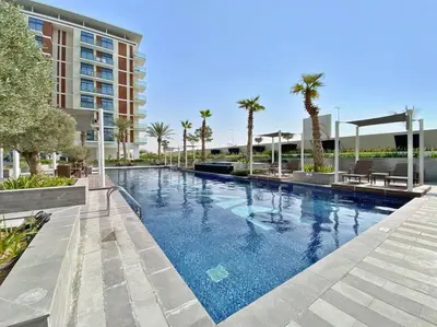a large swimming pool with palm trees and a building at StoneTree - Furnished 1BR minutes of drive away to Expo 2020 in Dubai
