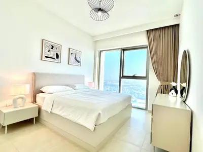 a white bedroom with a bed and a large window at Downtown Views 1BR - Dubai Mall, Fountain & Burj Khalifa access in Dubai