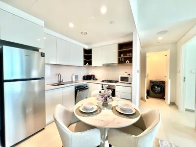 a kitchen with a table and chairs and a refrigerator at Downtown Views 1BR - Dubai Mall, Fountain & Burj Khalifa access in Dubai