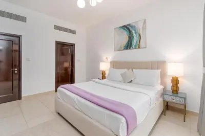 a white bedroom with a large bed and a table at Lux BnB Travo Tower I Private Garden I Lake View in Dubai