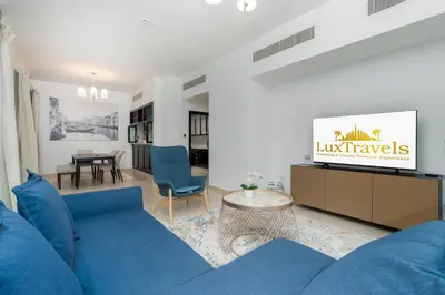 a living room with a blue couch and a table at Lux BnB Travo Tower I Private Garden I Lake View in Dubai