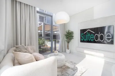 a white living room with a white couch and a tv at Crystal water lagoon living in District One in Dubai