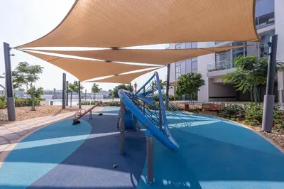 a child is playing on a slide in a playground at Crystal water lagoon living in District One in Dubai