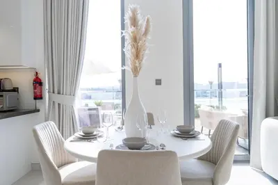 a white dining room with a white table and chairs at Crystal water lagoon living in District One in Dubai