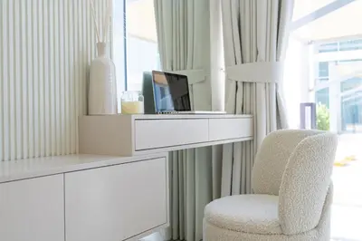 a white living room with a chair and a tv at Crystal water lagoon living in District One in Dubai