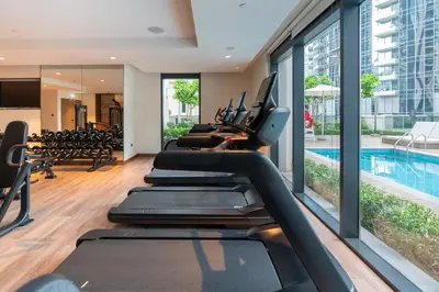 a gym with treadmills and a swimming pool at White Sage - Act One Tower in Dubai