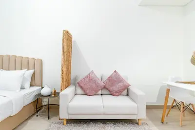 a living room with a white couch with pink pillows at Nice Studio in Azizi Riviera 32 - Dubai in Dubai
