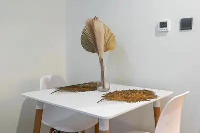a white table with a vase with a feather in it at Nice Studio in Azizi Riviera 32 - Dubai in Dubai