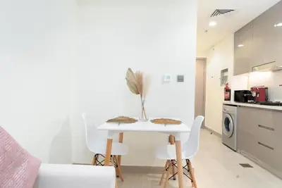 a white dining room table and chairs in a kitchen at Nice Studio in Azizi Riviera 32 - Dubai in Dubai