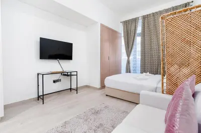 a white room with a bed and a tv at Nice Studio in Azizi Riviera 32 - Dubai in Dubai