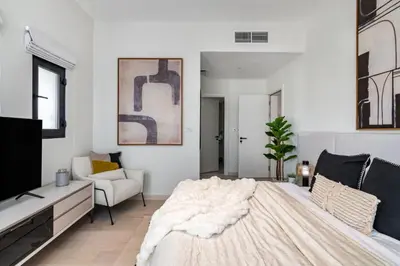 a bedroom with a large bed and a tv at Stunning Palm Villa with Rooftop Garden, Resort Style Pool and Beach by Exclusive Holiday Homes in Dubai