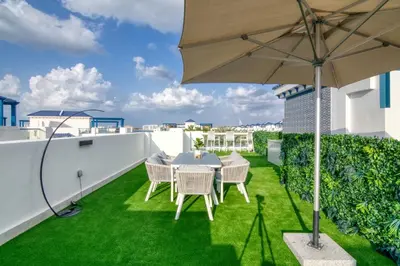 a patio with a table and chairs and an umbrella at Stunning Palm Villa with Rooftop Garden, Resort Style Pool and Beach by Exclusive Holiday Homes in Dubai