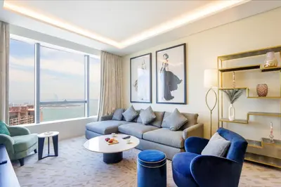 a living room with blue furniture and a large window at Livbnb Suites - 1BR w/ Sea View in Palm Tower in Dubai