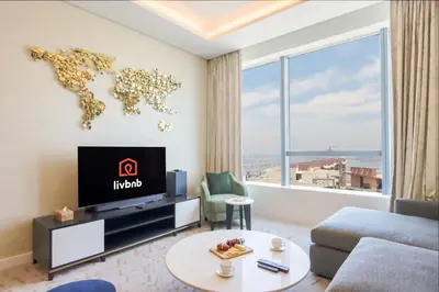 a living room with a tv and a world map on the wall at Livbnb Suites - 1BR w/ Sea View in Palm Tower in Dubai